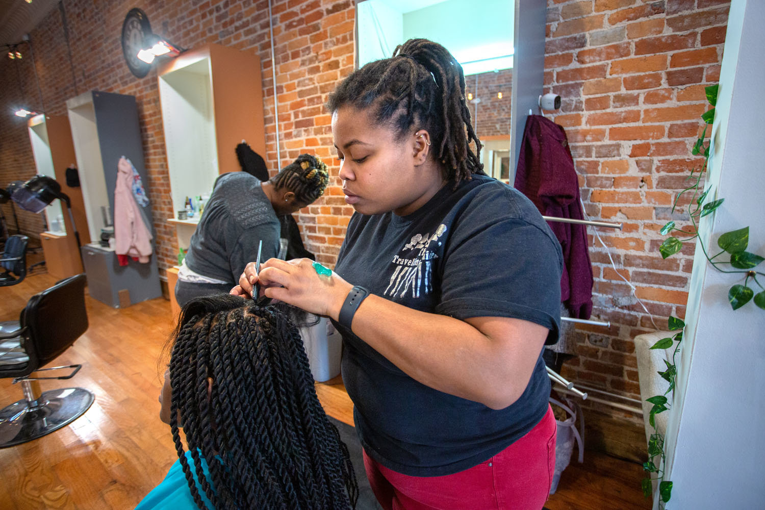 NICHE BUSINESS: Champale Love-Hudson styles a customer’s hair with a Senegalese braid at Springfield Braiding Co.’s new shop on Commercial Street.